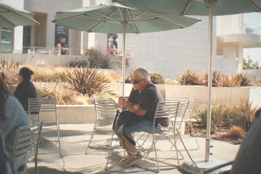 A museum cafe terrace with tables, umbrellas and a view over hills toward the ocean