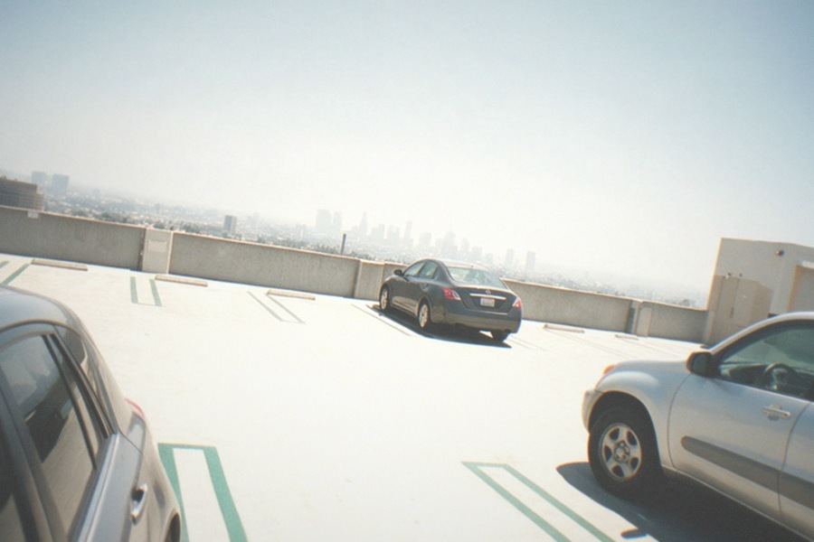 A winding park road below Griffith Observatory lined with cars parked along the shoulder