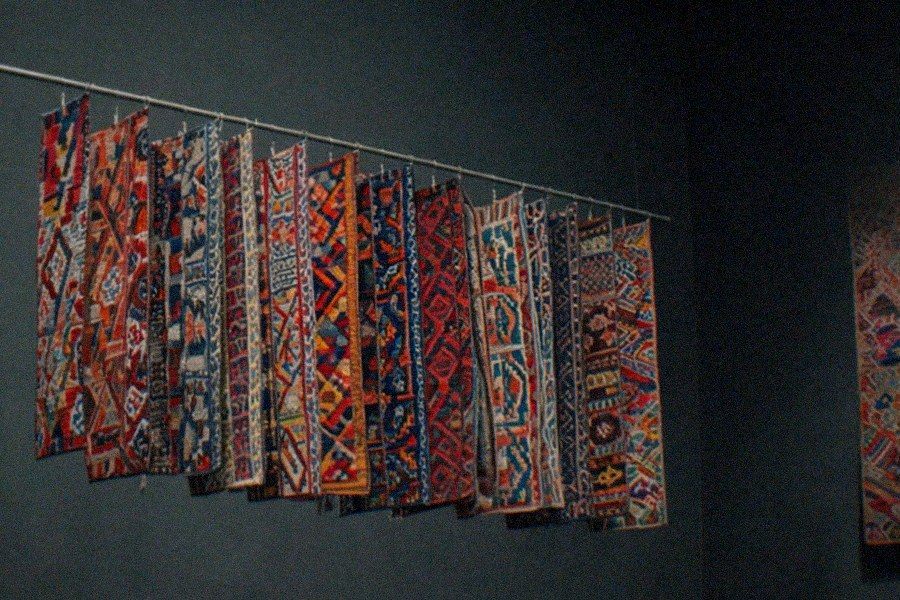 A gallery inside the Fowler Museum at UCLA displaying West African textiles and sculpture in glass cases under focused lighting
