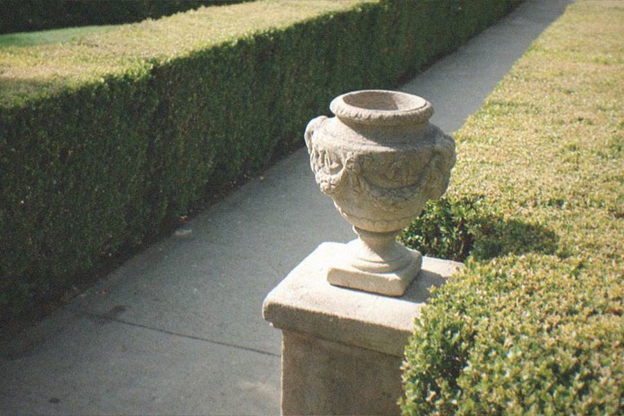 Formal garden with clipped hedges, fountain and museum building in the distance