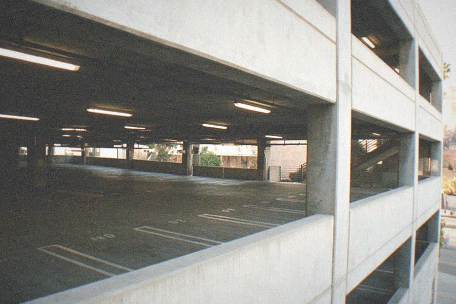 Parking structure with cars parked near a museum entrance on a sunny afternoon