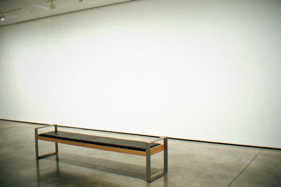 A museum gallery wall with European paintings hung salon style