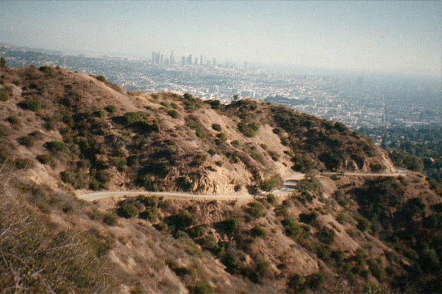 An observatory building with domes on a hilltop above a hazy city basin